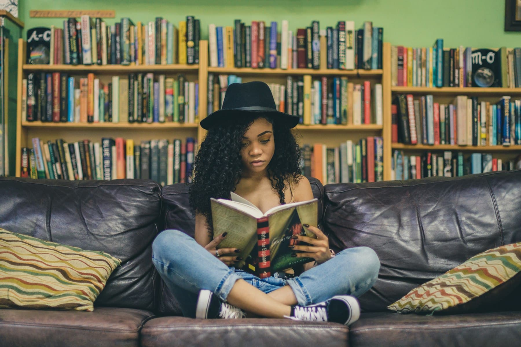 Young woman reading a book on a couch in soft daylight