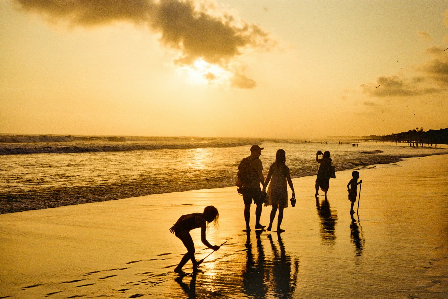 Family walking together along the shoreline at sunset