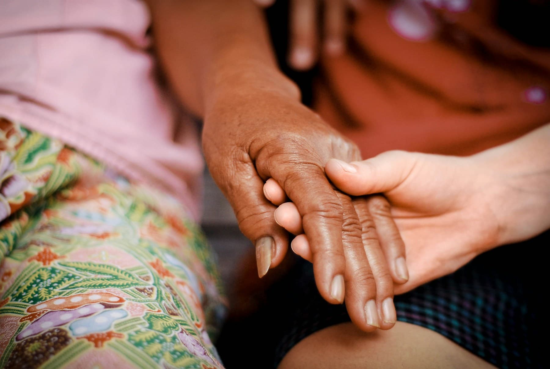 One person's hand resting gently over another's in comfort