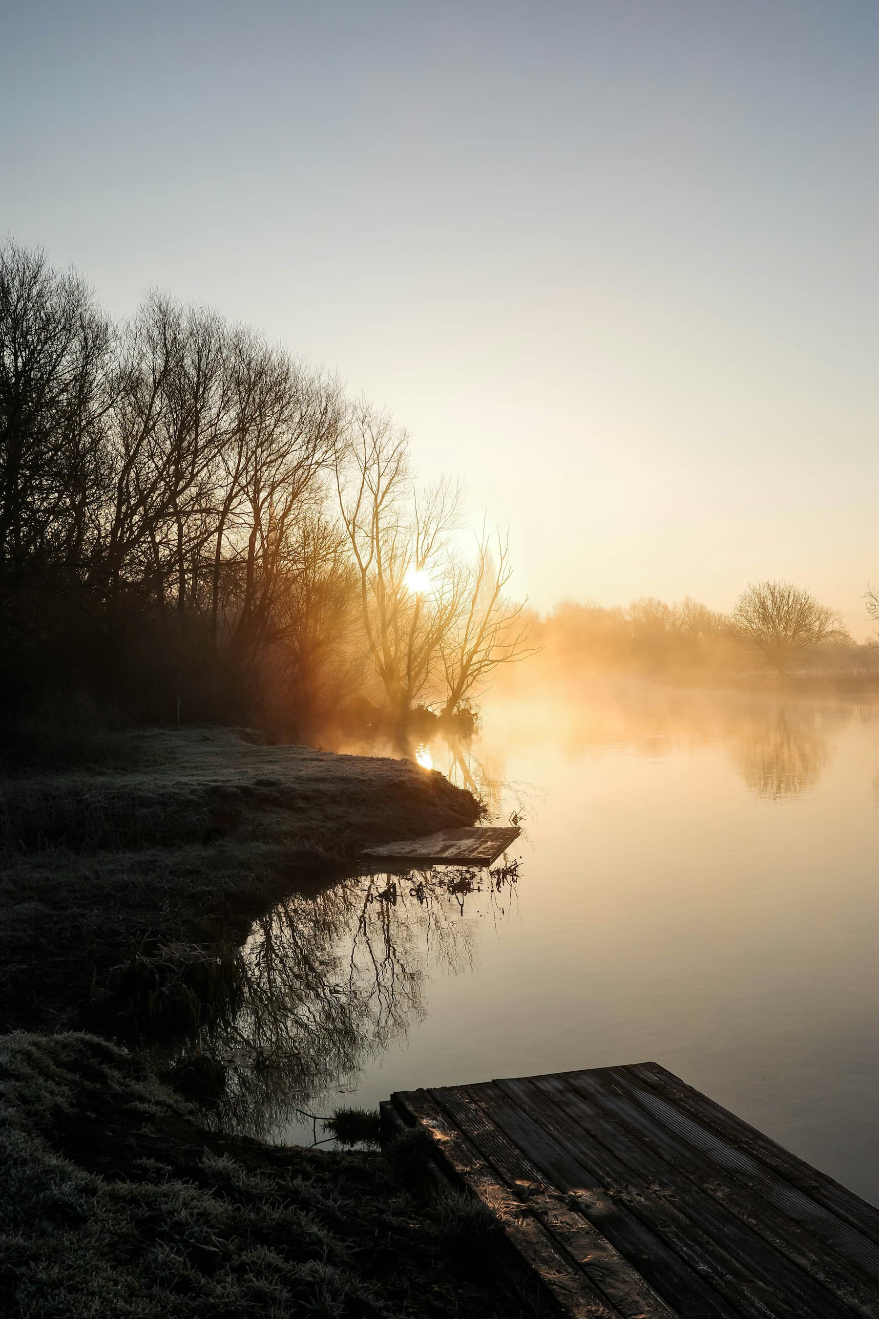 Still lake at sunrise with mist drifting over the water