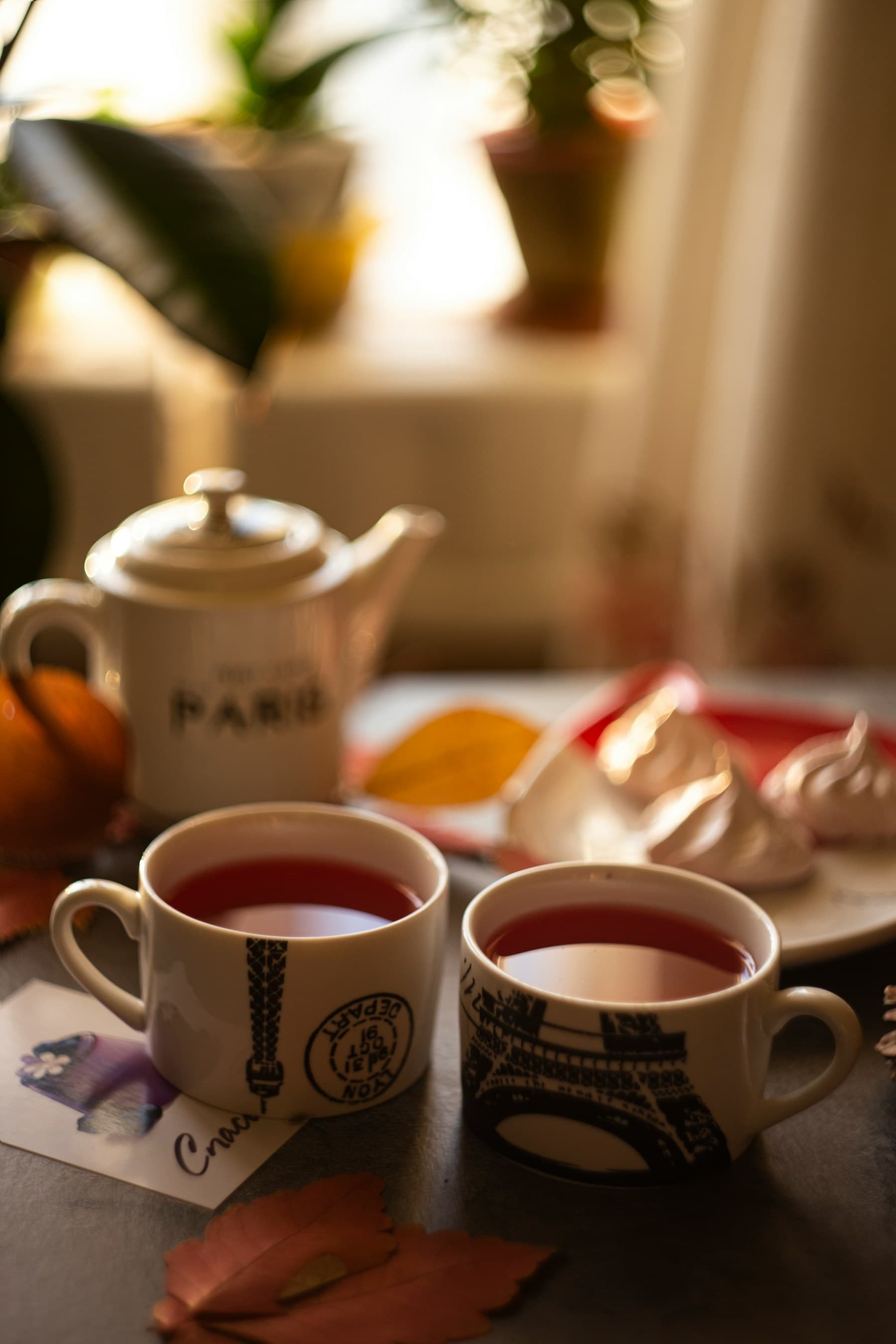 Two cups of tea poured on a table by a sunlit window